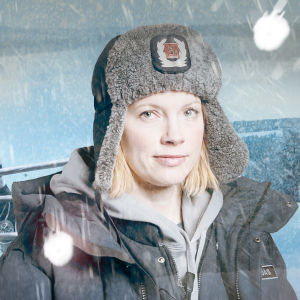 Maria Pudas (Saara Kotkaniemi) katsoo pienen hymyn kanssa kameraan. Taustalle lisätty luminen maisema ja Pudas nyrkkeilykehään.