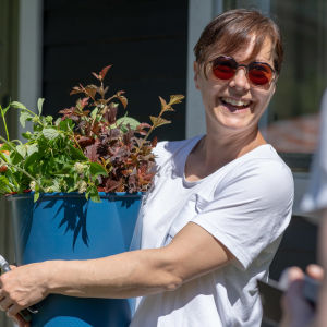 Puutarhuri Anna Palasmaa hymyilee sylissään ämpärillinen leikkokukkia
