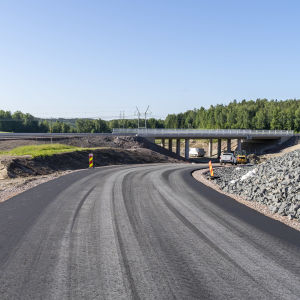 En nybyggd väg med ny asfalt. Vägen går under en bro. Det är sommar och sol. Karis, Läpp, riksväg 25.