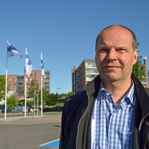 Jarmo Keskitalo poserar, i bakgrunden flaggor.