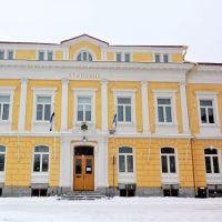 Ett gult gammalt stenhus, vinter, snö. Det står stadshus på byggnaden som har två våningar plus en mindre del högst upp i tredje våningen.
