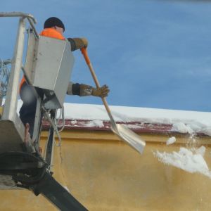 En man rensar taket från is och snö