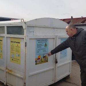 En man pekar på en container för sopor. 