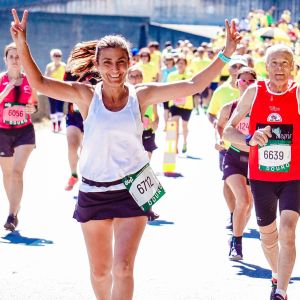 Maratonia juoksevat nainen ja mies näyttävät hymyillen voitonmerkkiä ja peukaloa kuvaajalle.