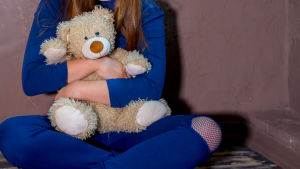 Omhändertagna barn behöver mycket stöd med sina sociala relationer. Ett barn med en teddybjörn i famnen.
