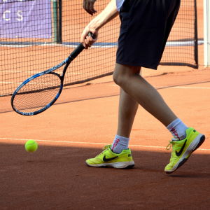 Tennis är en aktivitet med låg/medelrisk vad gäller coronaspridning. Benen på en tennisspelare som håller i ett tennisracket.