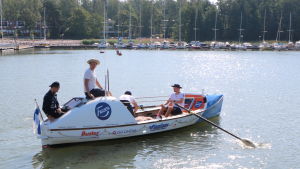 Valtteri Ikäheimo, Linus Lehto, Bernhard Forstén och Eddie Myrskog arbetar bra tillsammans. Oceanroddbåt med fyra män i. I bakgrunden Björkholmens metrostation.