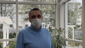 Här i Fylgias inglasade vinterträdgård kunde man låta bygga en ny mötesplats, funderar Peter Guss. Anhöriga skulle nå trädgården via innergården. Man i ljusblå tröja och vitt munskydd står i inglasat uterum.