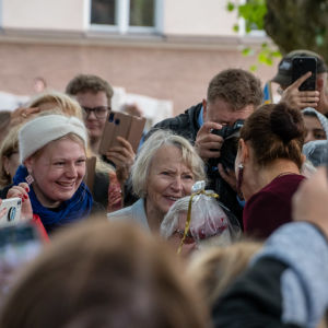 Kronprinsessan Victoria i en folkmassa, många kameror i luften. Victoria talar med några kvinnor som ser rörda ut.