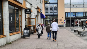 Det är inte så ofta man ser någon använda munskydd i gatubilden. Matbutiken tycks vara den vanligaste platsen att använda skydd. Personer som promenerar i stad, en kvinna bär munskydd.