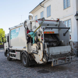 En sopbil kör på en kullerstensgata i en äldre stadsdel.