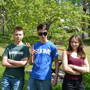 Tre ungdomar poserar framför en skogsglänta en varm sommardag.