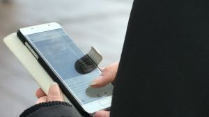 Vilka bilder kan man lägga ut på sin baby på sociala medier? "Jag lägger inga bilder där barnet visas negativt, utan neutrala, trevliga, fina och glada bilder", säger Catariina Salo. Tjej använder smarttelefon ute