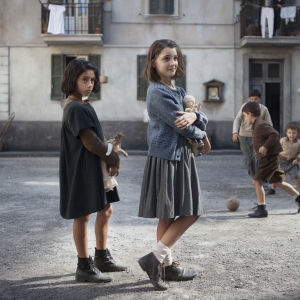 Lila (Ludovica Nasti) och Elena (Elisa Del Genio) står bredvid varandra på gatan och håller i varsin docka.
