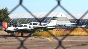 Flygplanen står skyddade innanför en inhägnad. Flygplan bakom ståltrådsstaket.
