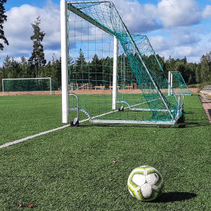 En fotboll bredvid ett mål på en fotbollsplan.