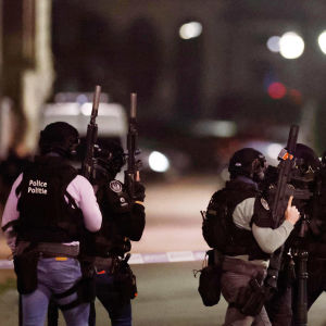 Aseistetut luotiliiveillä ja kypärillä varustautuneet poliisit kävelevät kadulla.