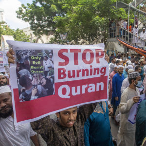 En demonstrant håller upp en affisch med texten Stop Burning Quran (Sluta bränna koranen) under en demontration mot koranbränning i Bangladesh.