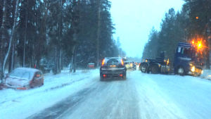 Riksväg 25 är smal och krokig mellan Karis och Lojo. Den tunga trafiken uppmanas ta vägen för att åka runt huvudstadsregionen, men olyckor sker ofta särskilt vintertid, säger Hettula. En isig landsväg där en bil står i diket och en långtradares dragbil står snett över vägen. Bilar kör försiktigt förbi.
