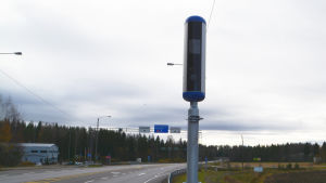 Så här ser de nya trafiksäkerhetskamerorna ut. Den här finns på Riksväg 6 i Lovisa. En avlång trafikkamera mot en molnig himmel.