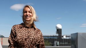 Ilona Láng är meteorolog och forskare vid meteorologiska institutet. En ung kvinna står på en kontorsbyggnads tak. Himlen är blå och hon ler och tittar in i kameran och ler.