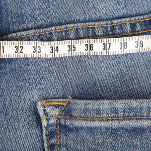 Närbild på ett par jeans med måttband ovanpå (illustrationsbild för övervikt).