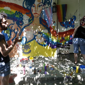 Deltagare i årets pridefestival i Istanbul målar regnbågens färger på en vägg under ett evenemang.