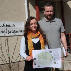 Jonas Pomrén och Kirsti Virkki är båda inblandade i parkens utformning. en kvinna och en man intill ett litet äppelträd framför en gul stenbyggnad med skylten miljö- och teknik