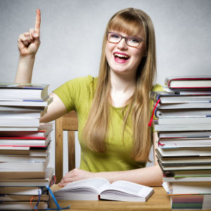 En glad kvinna med pekfingret utsträckt sitter bakom två högar av böcker.