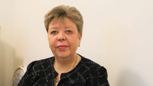 Mari Tocklin har jobbat med fastighetsförmedling i över 30 år och har aldrig sett ett lika stort utbud av hyreslägenheter i Åbo som nu. En kvinna med kort ljust hår och svart kavaj står framför en vit vägg.