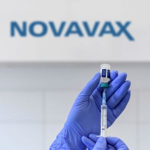 En sjukskötare håller i en dos av Novavax-coronaviruset samt en spruta.