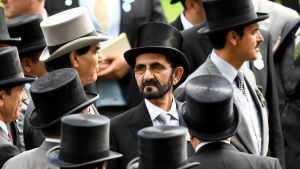 Shejk Mohammed (i mitten) tros ha tiotals barn med många olika kvinnor. Man i hatt omgiven av andra svartklädda män i hatt.