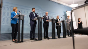 Fyra ministrar på presskonferens på avstånd, Anna-Maja Henriksson längst till vänster. Foto på avstånd av fyra ministrar i presskonferens.