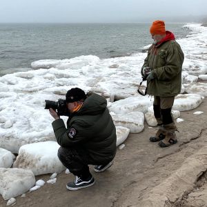Två män fotar på en strand, isblock, dimma.