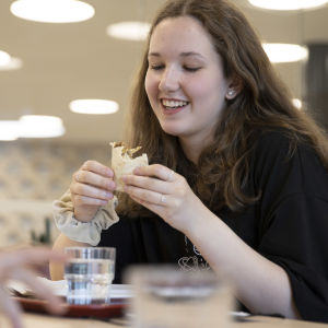 Kvinnlig skolelev äter skollunch, en vegetarisk tortilla.