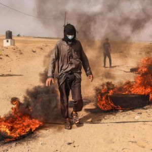En palestinsk demonstrant bränner bildäck vid Gazaremsan den 10 maj 2021.