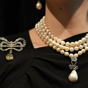 Ett pärlhalsband med en pärlor i flera rader och en droppformad pärla som hänger i det.