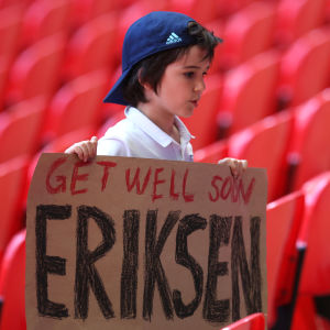 En pojke håller upp en skylt med texten "Get well soon Eriksen" där han står på läktaren under matchen mellan England och Krotatien.