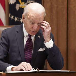 Joe Biden lukee papereita työpöytänsä ääressä huolestuneen näköisenä. 