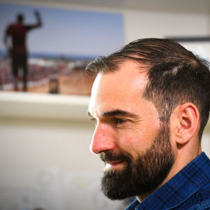 Gueorgiou vid sitt arbetsbord med ett foto av sig själv i bakgrunden