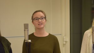 Emilia Ekström spelar Ebba i pjäsen. Emilia Ekström står vid en mikrofon och sjunger.