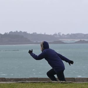 Man kämpar för att ta sig fram i den hårda vinden vid stranden i den franska kuststaden Saint-Malo.