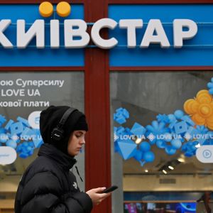 En kvinna med en telefon går förbi telekombolaget Kyivstar i Ukraina.