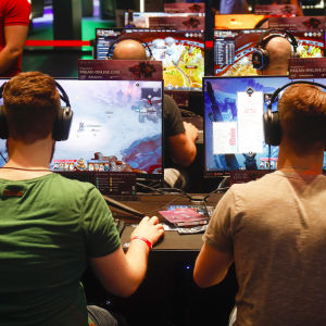 Två män sitter framför varsin dataskärm och spelar. Männen sitter med ryggen mot kameran
