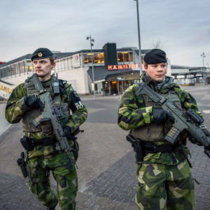 Beväpnade soldater patrullerar på en gata. 