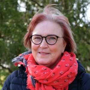 Kvinna står framför träd. 