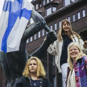 Naisia Kolmen sepän patsaan päällä Suomen lipun kanssa juhlistamassa jääkiekon MM-voittoa 1995
