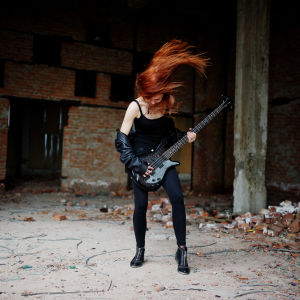 Svartklädd kvinna spelar gitarr och slänger med håret.