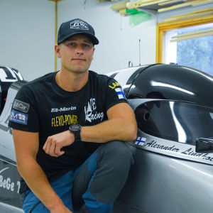 Alexander Lindholm sitter på huk vid sin gråa formel 4 racerbåt. 