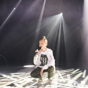 Hugo käld står på huk och sjunger som gästartist under MGP 2018.